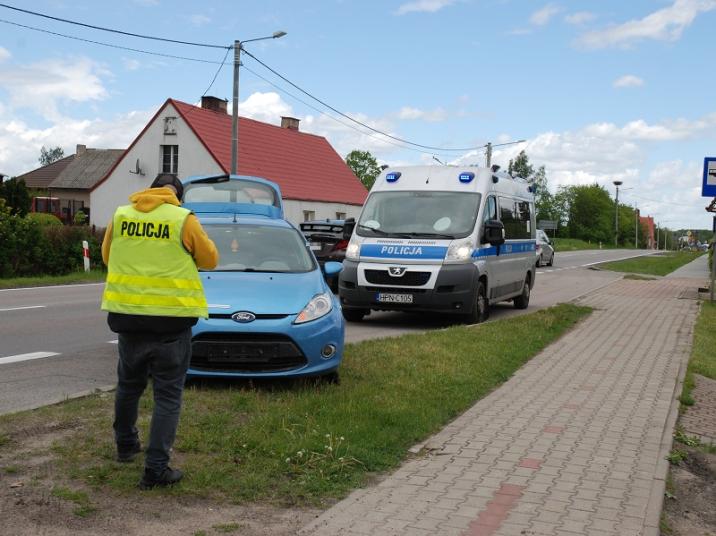 fot&#x2e;&#x20;KPP&#x20;w&#x20;Człuchowie&#x2e;&#x20;Na&#x20;pierwszym&#x20;planie&#x20;Policjant&#x20;w&#x20;żółtej&#x20;kamizelce&#x2c;&#x20;w&#x20;tle&#x20;ścigany&#x20;samochód&#x20;oraz&#x20;radiowóz&#x2e;